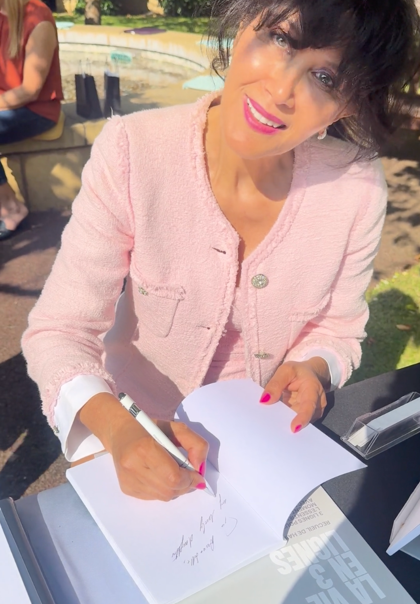 Fern Jean-Joseph in pink jacket doing a book signing outdoors